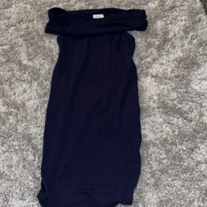 Marinblå offshoulder klänning Kappahl - Snygg marinblå klänning från Kappahl i offshoulder-modell. Klänningen är kort och har en enkel, stilren design utan mönster eller extra detaljer. Perfekt för dig som gillar en klassisk look med en modern twist.