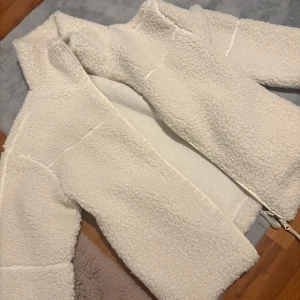 Vit teddyjacka med dragkedja - Mysig och oversized vit teddyjacka med hög krage och hel dragkedja framtill. Ord pris 500 säljer för 300 har använt den en gång men jag tog för liten storlek så känner att den sitter lite  akward på mig och vill köpa om den i lite större storlek men kan ej returnera pga borttagen prislapp…