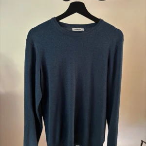 Blå stickad tröja från J.Lindeberg - Blå stickad tröja från J.Lindeberg i en skön blandning av merinoull, bomull och akryl. Storlek M tveka inte på att höra av er 
