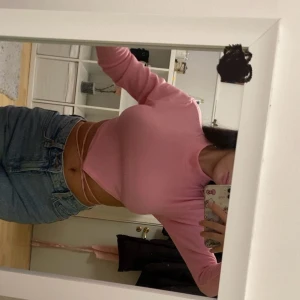 Rosa croppad topp med snörning - Säljer en ljusrosa croppad topp med långa ärmar och öppen rygg. Toppen har snygga snörningsdetaljer som knyts i ryggen och är gjord i ett ribbat material som sitter tight. 