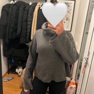 Grå ribbad polotröja med vida ärmar från bikbok - Mysig grå polotröja med ribbad struktur och oversized passform. Tröjan har höga vida ärmar och en större polokrage. Perfekt för lager-på-lager under kalla dagar. 