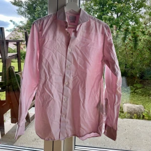 Ljusrosa skjorta från Selected Homme - Snygg ljusrosa skjorta från Selected Homme i slim fit-modell. Skjortan har klassisk krage, långa ärmar och vita knappar framtill. Tillverkad i bomull och är enkel att stryka. Funkar som en snygg skjorta att ha uppknäppt till ett linne eller som vanligt. Säljes åt min pojkväns lillebror som växt ur.💞