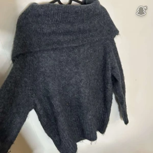 Mörkblå/grå stickad polotröja H&M - Mysig mörkblå/grå stickad off shoulder tröja från H&M i storlek S. Tröjan har en bred polokrage och är långärmad med en loose fit. Perfekt för kyliga dagar och enkel att styla med jeans eller kjol.