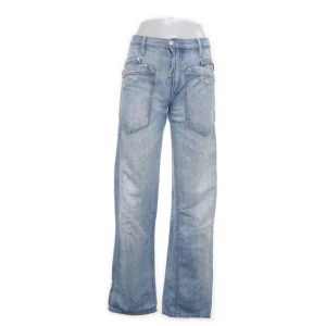 Ljusblå vintage låg midjade jeans med stora fickor - Säljer ett par ljusblå jeans med bred passform och stora, markerade fickor både fram och bak. Jeansen har en avslappnad baggy stil och är tillverkade i klassiskt denimtyg. Perfekta för dig som gillar en loose och chill vibe.