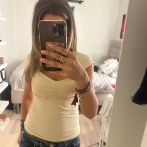 Ljusgul kortärmad topp i bomull - En enkel och fräsch ljusgul topp med korta ärmar och lätt v-ringad hals. Modellen är figurnära och passar perfekt till jeans eller kjol. Tillverkad i mjuk bomull som känns skön mot huden. Perfekt för varmare dagar.