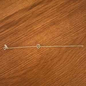 Silverarmband med alien-berlock från Maria Nilsdotter  - Snyggt och tunt silverfärgat armband med en liten alien-berlock i mitten. Kedjan är smal och har justerbar längd med klassisk låsning. Perfekt för dig som gillar unika detaljer och vill sticka ut med ett coolt smycke. Till den sista länken är den ca 19 cm och den första ca 15 cm. Köptes för ca 1000 kr. Frakt betalt köparen!!!!!!!