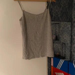 Ljusgrå linnetopp med smala axelband - Enkel och stilren ljusgrå linnetopp med smala axelband. Perfekt att matcha med jeans eller kjol för en clean look. Tunt och mjukt material som känns skönt mot huden.