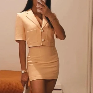 Aprikos kortkjol i figurnära modell med en snygg kavaj - Säljer en aprikos kortkjol med tight passform och hög midja. Kjolen och kavajen är enkel och stilren, perfekt att matcha med en kavaj eller crop top. Endast testat, från MNG