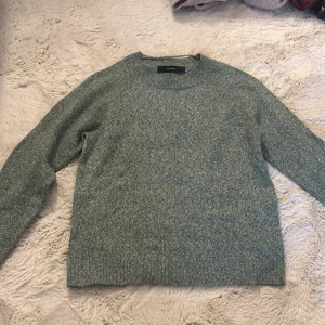 Grön stickad tröja från Vero Moda - Snygg grön stickad tröja från Vero Moda i storlek XS. Tröjan har en rund halsringning och långa ärmar, perfekt för kyliga dagar. Den är mjuk och har en enkel, klassisk design med ribbade muddar vid hals, ärmslut och nederkant. Passar dig som gillar stilrena och bekväma plagg. Nypris är 300.
