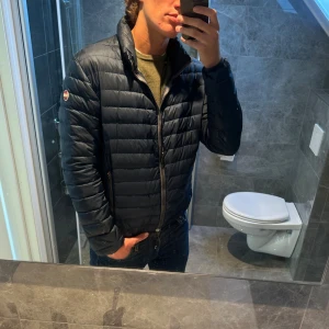 Marinblå Colmar dunjacka  - Säljer en mörkblå dunjacka från Colmar. Jackan är i bra skick. Jag på bilden är 188cm och bär storlek 52 vilket motsvarar en M eller en större S. Nypris för denna ligger runt 3000kr. Hör av er vid frågor;)