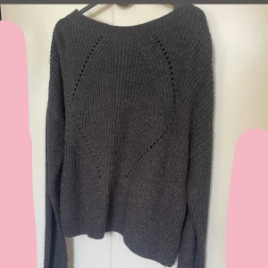 Mörkgrå stickad tröja med håldetaljer - Mysig mörkgrå stickad tröja med lång ärm och snygga håldetaljer framtill som ger en cool struktur. Tröjan har en något lös passform och bredare rund halsringning. Den är i storlek xxl men den passar på mig som har S. (Väldigt små storlekar) 