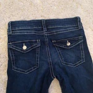 Mörkblå bootcut jeans från Gina Tricot - Snygga mörkblå jeans från Gina Tricot med bootcut passform. Jeansen har kontrastsömmar, klassiska fem fickor och coola ficklock med knapp bak. Tillverkade i stretchig denim för skön passform. Passar till allt. Köpt från barnstorlekar! Säljer för att de är för små!💕☺️