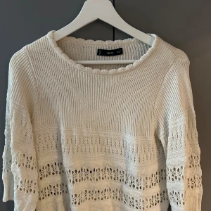 Vit stickad tröja från Mango - Vit stickad tröja från MNG med bred halsringning och virkade detaljer. Tröjan har trekvartsärm.
