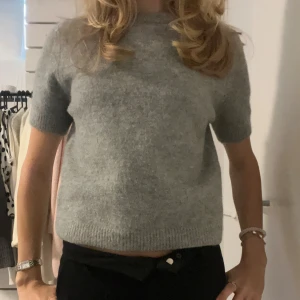 Grå stickad kortärmad tröja från Zara - Supermjuk och enkel grå stickad tröja från Zara med korta ärmar och rund hals. Perfekt till lager-på-lager eller bara som den är. Tröjan har en rak passform och ribbade kanter vid ärmslut och nederkant. Den är i väldigt bra skick bara använd fåtal gånger💕