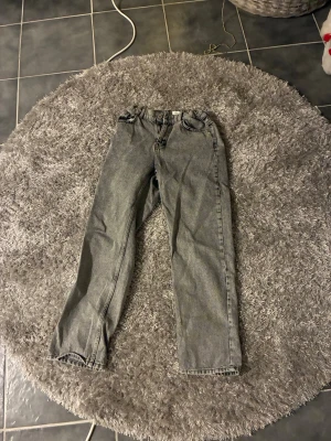 Grå straight jeans med normal passning - Säljer ett par grå jeans med märket GRUNT som har en klassisk femficksdesign och rak passform. Jeansen har normal midja och är tillverkade i ett slitstarkt denimtyg. Färgen är tvättad grå vilket ger en cool vintagekänsla. Perfekta att styla med hoodies eller t-shirts. Om man har frågor angående byxorna så är det bara att fråga.