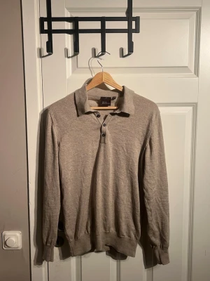 Beige pikétröja från Oscar Jacobson - Snygg beige pikétröja från Oscar Jacobson med klassisk krage och tre svarta knappar framtill. Om du har mer frågor eller vill se mer bilder är det bara att fråga