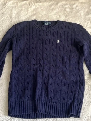 Mörkblå stickad tröja från Ralph Lauren - Säljer en mörkblå kabelstickad tröja från Ralph Lauren. Den är använd ett fåtal gånger och i bra skick. Pris kan diskuteras och fråga gärna!🥰