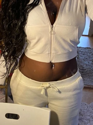 Vit croppad zip-hoodie - Säljer en vit croppad hoodie med dragkedja och huva. Tröjan har långa ärmar, två stora fickor framtill och ribbad nederkant. Perfekt för chill dagar och enkel att matcha med mjukisbyxor. Materialet är mjukt och känns som fleece.