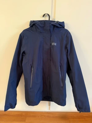 Helly Hansen skidjacka - Snygg marinblå skidjacka från Helly Hansen med borttagbart foder för att använda jackan som en skaljacka