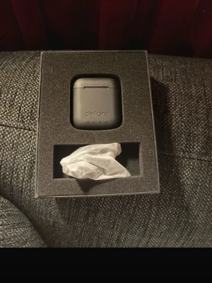 Defunc TRUE GO SLIM - Defunc TRUE GO SLIM trådlösa hörlurar med laddningsetui. Svart färg, kompakt design och tydliga LED-indikatorer. Kapacitet: 400mAh. Hörlurarna ser ut att vara i gott skick utan synligt slitage. Perfekt för musik och samtal på språng.