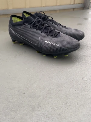 Nike Air Zoom svarta fotbollsskor - Säljer ett par svarta Nike Air Zoom fotbollsskor. Perfekta för dig som vill ha grymt grepp på planen och snygg stil.