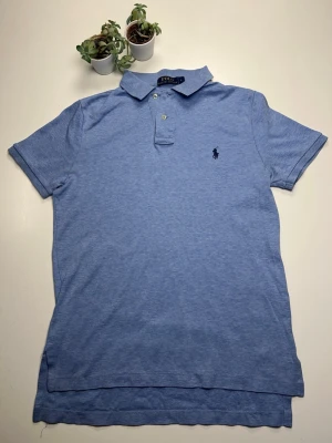 Blå piké från Polo Ralph Lauren - Klassisk ljusblå pikétröja från Polo Ralph Lauren med korta ärmar, krage och två knappar framtill. Ikoniska loggan broderad på bröstet. Perfekt nu för sommaren och vår som närmar sig ⚡️