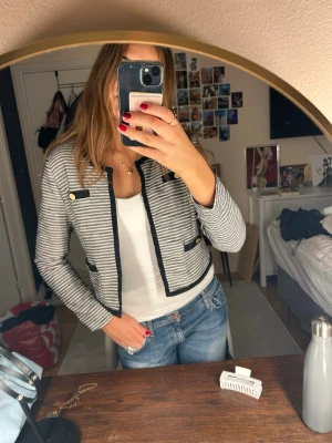 Kavaj från STOCKH LM - Säljer en snygg, kort kavaj från STOCKH LM i svartvitt randigt mönster. Jackan har guldfärgade detaljer. Den är i storlek 42 men den passar på mig som har storlek S