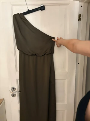 Långklänning ASOS - Säljer en stilren långklänning från ASOS i storlek 38. Klänningen har en snygg one shoulder-design och är gjord i ett mjukt, lätt material som faller fint. Perfekt till bal eller liknande. 