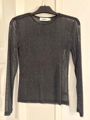 Glittrig långärmad topp från Kappahl - Säljer en glittrig svart långärmad topp från Kappahl. Toppen är tunn och genomskinlig. Använd 1 gång💕