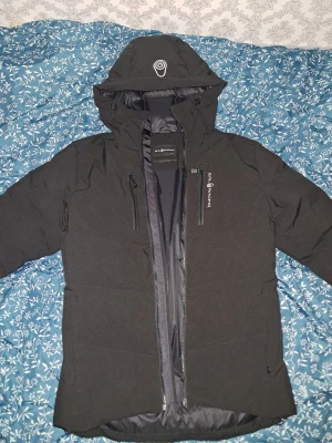 Svart Sail Racing Patrol down jacket  - Jackan är använd bara 3 gånger, jackan har huva, flera dragkedjeförsedda fickor och är fodrad. Perfekt för kalla dagar. Pris kan diskuteras!!! Org pris: 4000kr