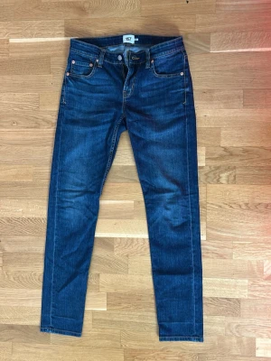 Blå jeans från 157 - Snygga blå jeans från 157 med klassisk femficksdesign. Jeansen har en mörk tvätt och kontrastsömmar samt ett brunt läderpatch bak i midjan. Perfekta till vardags och passar till det mesta. Tillverkade i slitstarkt denimtyg.