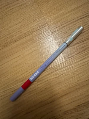 Kosas HOTLINEK läppenna röd - Säljer en Kosas HOTLINEK läppenna i färgen Extra. Pennan har en snygg lila kropp med röd markering och ett silverfärgat lock. Perfekt för att definiera läpparna med en krämig och pigmenterad formula.