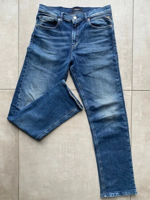 Blå Replay jeans straight fit - Säljer ett par klassiska blå jeans från Replay med fem fickor och snygga slitningar. Jeansen har rak passform och normal midja, tillverkade i mjukt denimtyg. Perfekta till en avslappnad look och funkar året runt.