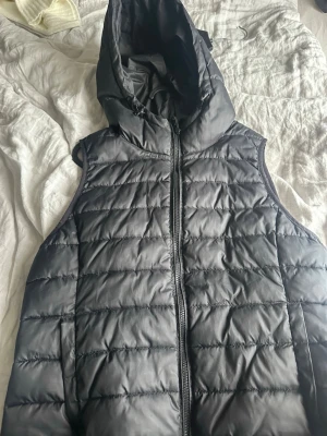 Svart dunväst med huva från ONLY, L/XL - Snygg svart dunväst från märket only i storlek L/XL. Stilren i mycket bra skicka! Använd endast fåtal gånger. 