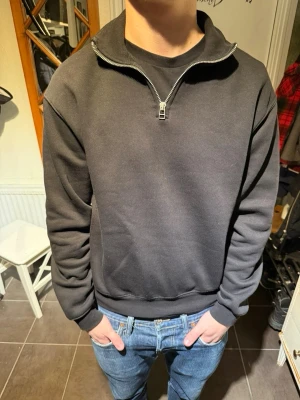 Zara halfzip  - En svart sweatshirt med halfzip och hög krage. Tröjan har ribbade muddar vid ärmslut och midja, samt en avslappnad passform. Perfekt för en chill och stilren look. Materialet ser ut att vara mjuk bomullsblandning.