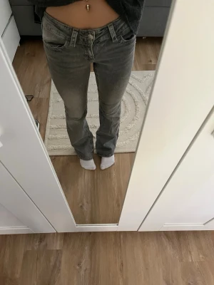 Gråa bootcut jeans med låg midja - Säljer ett par gråa bootcut jeans med låg midja. Jeansen har klassisk femficksdesign och raka ben med lätt utsvängning nedtill. Perfekta för dig som gillar en avslappnad men ändå snygg look.