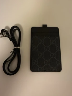 Svart plånbok med rem - Säljer en snygg svart plånbok med G på och en rem 