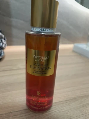 SÖKER!! Victoria's Secret Mango Temptation - SÖKER!!! Fräsch parfym från Victoria's Secret i doften Mango Temptation. Flaskan är cylindrisk med guldigt lock och etikett, och innehåller 250 ml. Doften har inslag av mango och hibiskusblomma. Perfekt för dig som gillar fruktiga och blommiga toner. Helst oanvänt.