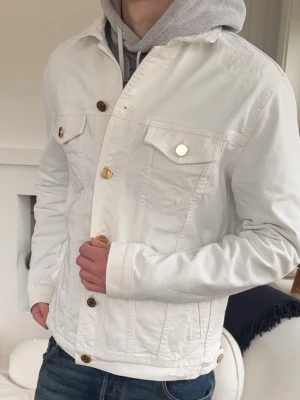 Vit overshirt jacka från Jacob Cohën - Nypris: 7500kr+ Snygg vit overshirt från Jacob Cohën med klassisk rak passform. Jackan har två bröstfickor med lock och guldiga knappar framtill. Tillverkad i kraftigt denimtyg som ger en exklusiv känsla. Perfekt för dig som vill sticka ut med en clean och stilren look.