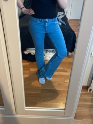 Blå bootcut jeans i klassisk modell - Säljer ett par ljusblå bootcut jeans med normal passform och klassisk femficksdesign. Jeansen har låg midja och är tillverkade i mjukt denimtyg som ger en skön känsla. Perfekta till en enkel t-shirt eller hoodie. Aldrig använda💞