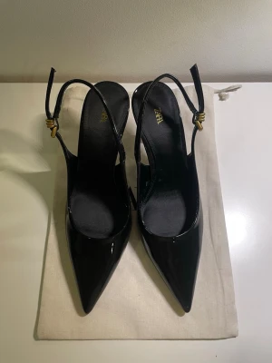 Svarta lackpumps med spetsig tå från Zara - Snygga svarta klackskor från Zara i glansigt lackmaterial med spetsig tå. Storlek 37 och klackhöjd 8 cm. Använt endast 1 gång och säljer pga fel storlek.