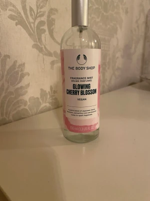  Cherry Blossom mist - Fräsch och blommig doftmist från The Body Shop med noter av japansk körsbärsblomma. Flaskan är genomskinlig med rosa och vit etikett och har en silverfärgad spraykork. Innehåller och är vegansk.