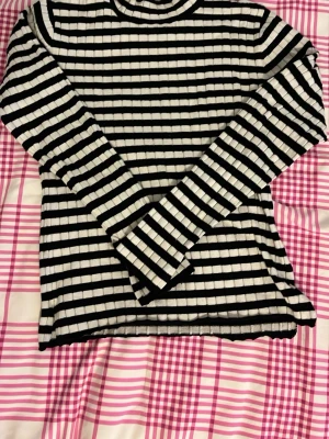 Svartvit randig tröja från lager 157 - Säljer en långärmad svartvit randig tröja från lager 157. Tröjan har smala horisontella ränder och är tillverkad i ett mjukt, ribbat material. Perfekt för en stilren och avslappnad look.