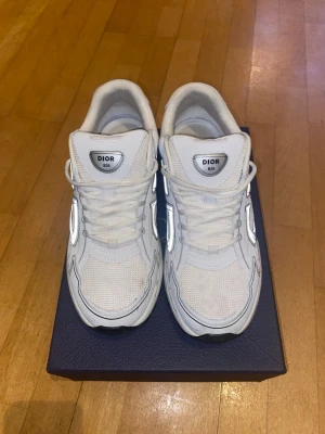 Dior B30 White - Sneakers Dior B22 👟 Dior B22 sneakers i vitt, med reflexdetaljer. Levereras med originalkartong och tillbehör.  ⭐️ Skick: 9/10 🎨 Färg: Vit 📦 Snabb och noggrann frakt