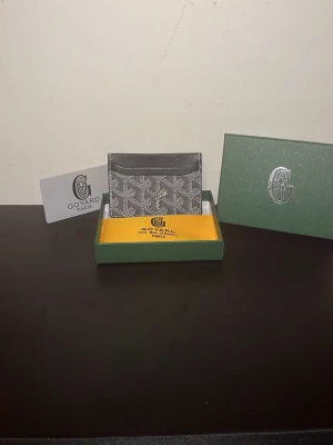 Svart och grå Goy4ard plånbok - Snygg svart och grå plånbok från Goy4ardmed det klassiska mönstret och flera fack för kort. Kommer med original ask och dustbag. Perfekt för dig som vill ha något stilrent och exklusivt i fickan.