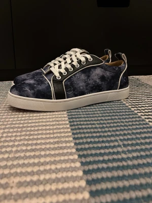 Christian Louboutin skor - Snygga sneakers i blått med unikt cirkelmönster och vita kontrastsömmar. Skorna har vita snören, vit sula och svarta paneler på sidorna. Perfekta för dig som vill sticka ut med en cool och modern stil. kommer med dustbag