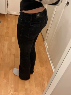 Svarta LTB jeans i storlek W25/L30 - Svarta LTB low bootcut jeans med klassisk femficksdesign och rak passform. Jeansen är lowwaist och är tillverkade i ett mjukt bomullsmaterial med lite stretch för extra komfort. Perfekta för en stilren och enkel look.