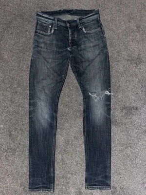 G-star raw 01 med slitningar - Snygga mörkblå slim jeans med slitning på ena knät och klassiska fem fickor. Jeansen har en smal passform och cool tvättad look, perfekta för en trendig streetstyle. Materialet är jeans och de har dragkedja och knapp framtill. 30:32! Litet hål i skrevet