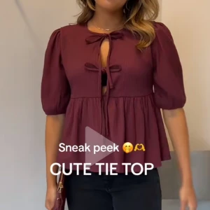 Vinröd blus med knyt och puffärm - Supersöt vinröd blus med två knyt framtill och puffiga halvlånga ärmar. Blusen har en lös passform och lätt rynkad nederdel som ger en flowy känsla. Perfekt att styla med jeans eller kjol för en trendig look.