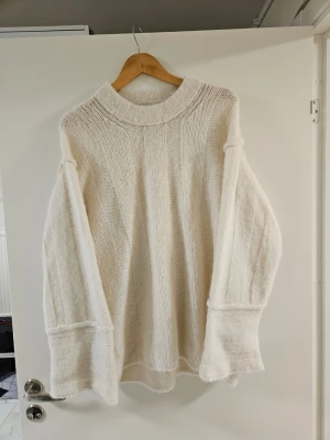 Oversized vit stickad tröja - Säljer en oversized vit stickad tröja med bred polokrage och vida ärmar. Tröjan har en mjuk och luftig känsla, perfekt för lager på lager. Passar dig som gillar en avslappnad och trendig stil.